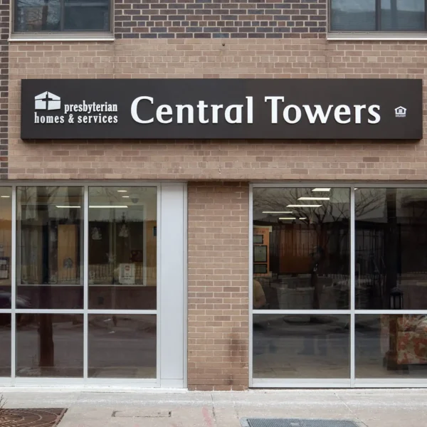 A brick building features a sign reading "presbyterian homes & services Central Towers" above glass doors and windows at street level.