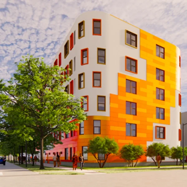 A modern, six-story building with a white and orange facade, large windows, and trees lining the sidewalk under a partly cloudy sky.