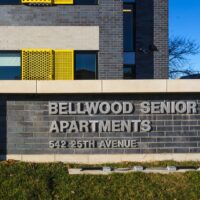 The exterior sign for Bellwood Senior Apartments at 542 25th Avenue is displayed on a brick wall outside a modern building.