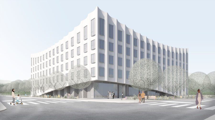 A modern, white, five-story building with large windows stands on a street corner, surrounded by trees and people walking or sitting nearby.