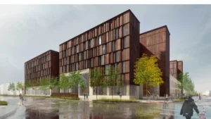 A modern multi-story building with a dark rust-colored facade and large vertical windows, surrounded by trees and people walking on a wet sidewalk.