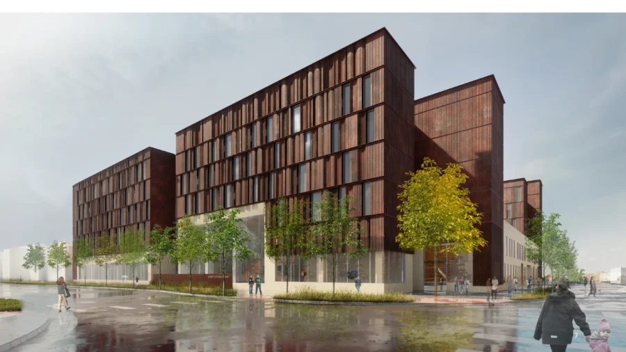 A modern multi-story building with a dark rust-colored facade and large vertical windows, surrounded by trees and people walking on a wet sidewalk.