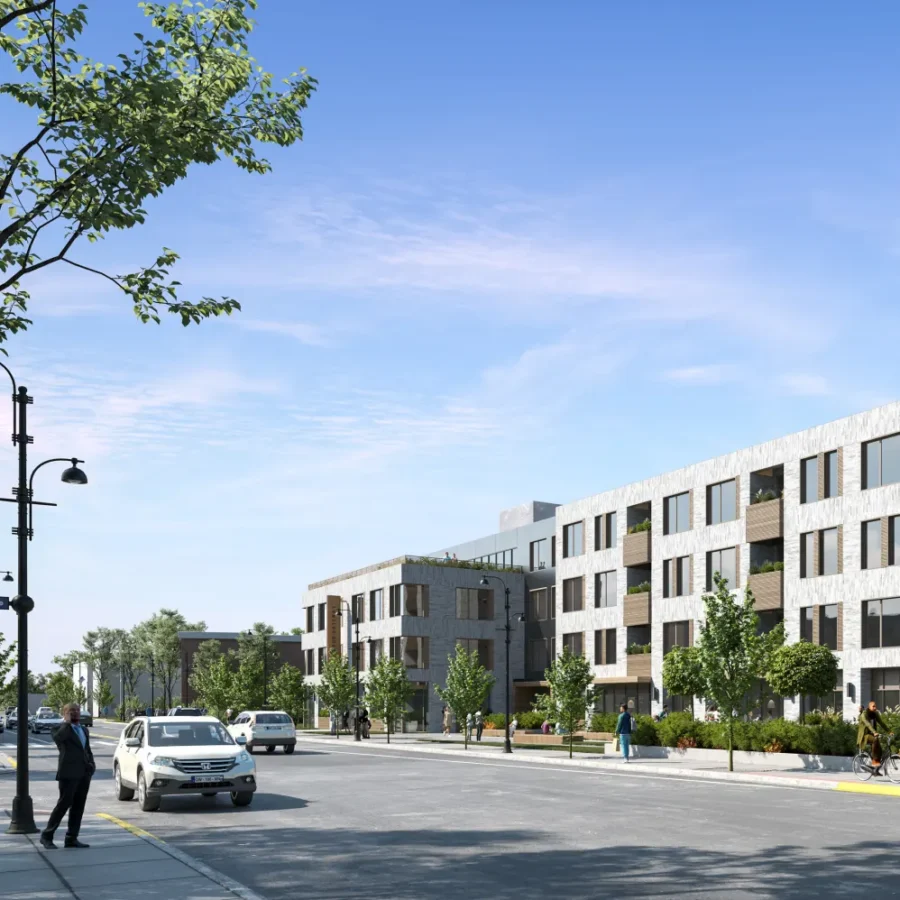 Modern four-story apartment building with large windows, trees, and people walking on a sunny street; several cars are parked and driving along the road.
