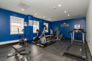 Bryn Mawr Belle Shore fitness center with a treadmill, elliptical machines, stationary bike, and weight bench on a wood-look floor.