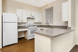 A kitchen with white cabinets, speckled countertops, a white gas range, and a white refrigerator.