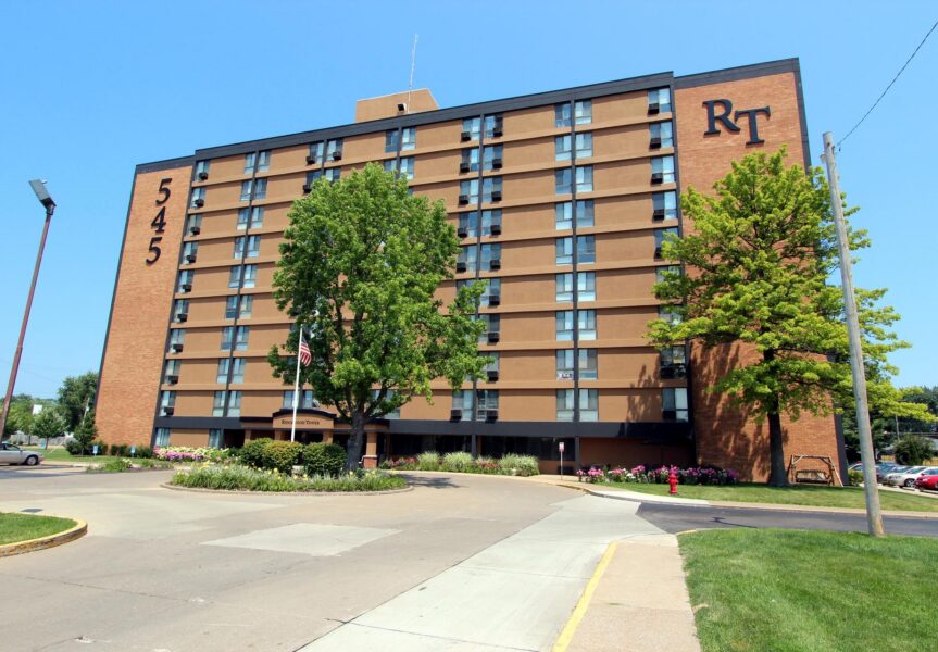 A multi-story brown brick apartment building named “Ridgewood Tower” with the numbers “545” and letters “RT” on the exterior.