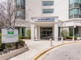 The entrance to Maple Pointe Apartments at 150 West Maple, featuring a sign with the building name and a glass-paned doorway.